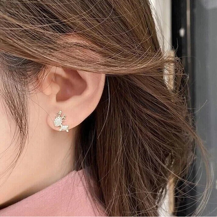 Woman wearing Gold Zircon Reindeer Earrings, against a blurred background.
