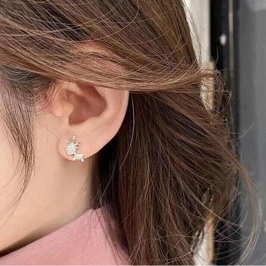Woman wearing Gold Zircon Reindeer Earrings, against a blurred background.