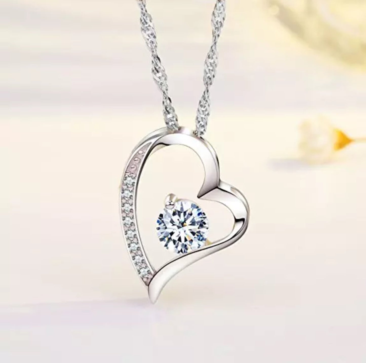 A silver heart-shaped necklace with a cubic zirconia embellishment in the center.