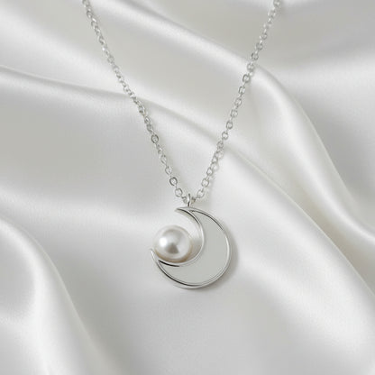 Silver Crescent Moon Pearl Necklace on a satin surface