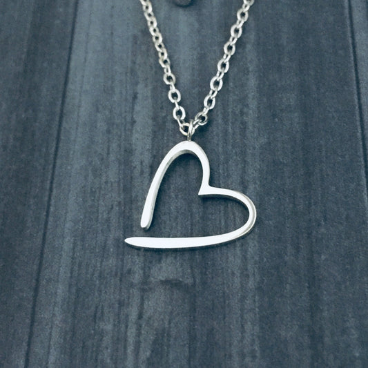 Silver heart-shaped pendant necklace on a wooden surface